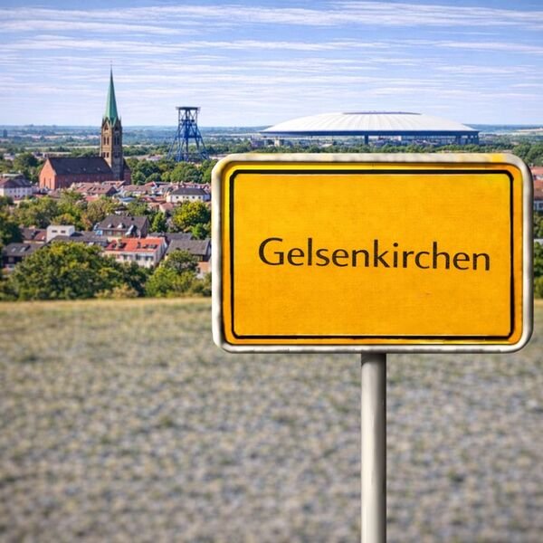 Gelbes Ortsschild Gelsenkirchen mit Stadt im Hintergrund